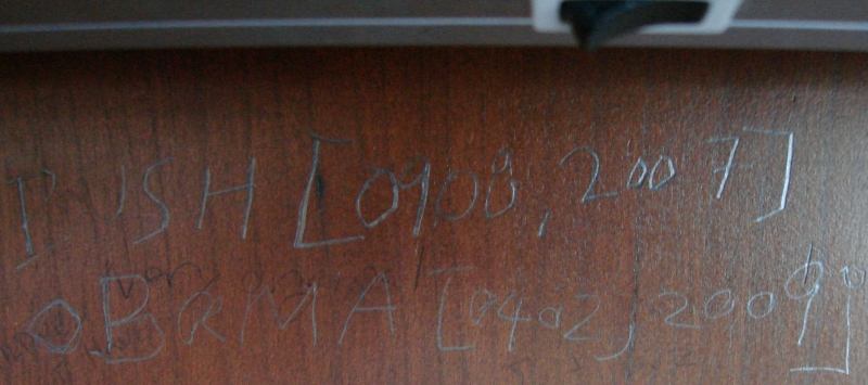 Close up of writing on a carrel wall. One line says "Bush O908, 2007" and the next says "Obama 0404, 2009"